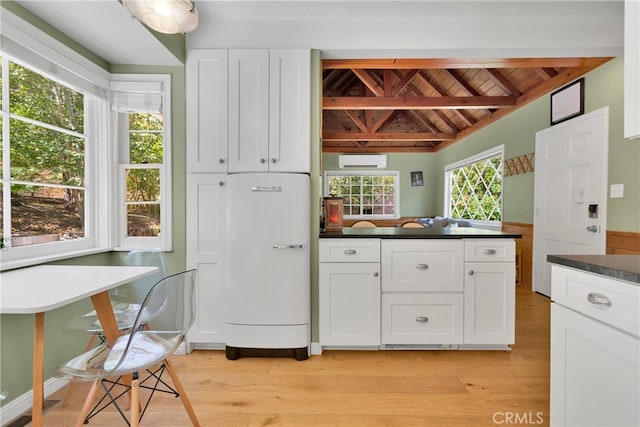 kitchen featuring white cabinets, refrigerator, light hardwood / wood-style flooring, and a wall mounted AC