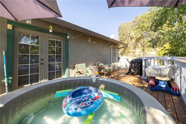 view of pool featuring a wooden deck and french doors