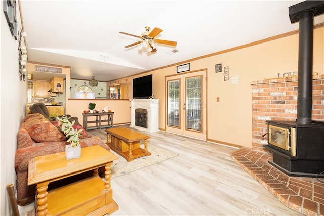 living room featuring a wood stove, crown molding, ceiling fan, hardwood / wood-style floors, and vaulted ceiling