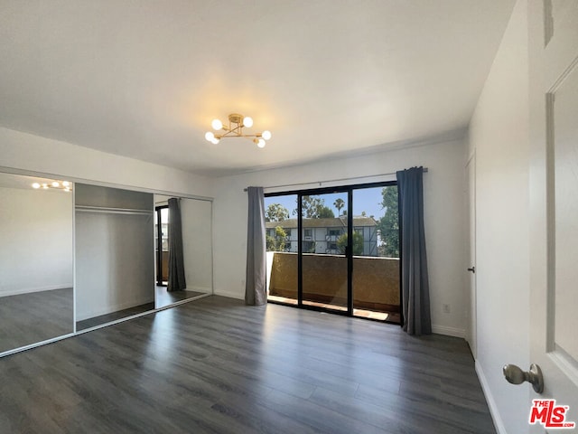 unfurnished bedroom with a chandelier, a closet, dark hardwood / wood-style floors, and access to exterior