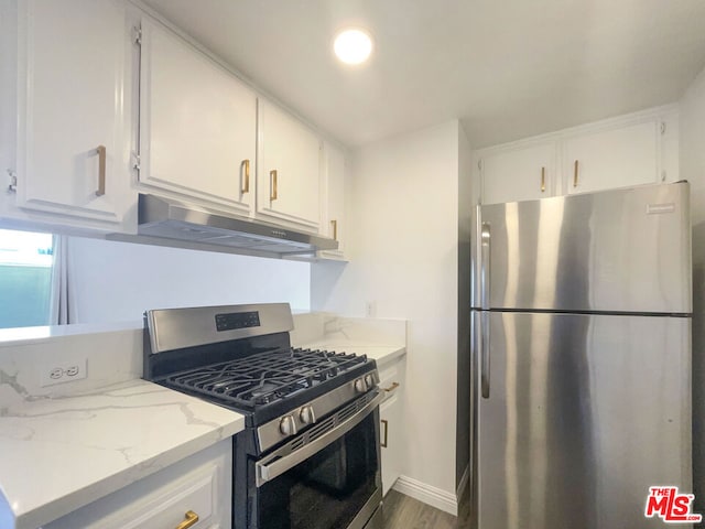 kitchen with light stone counters, hardwood / wood-style floors, stainless steel appliances, and white cabinets