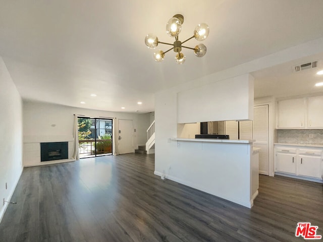 unfurnished living room with a notable chandelier and dark hardwood / wood-style flooring