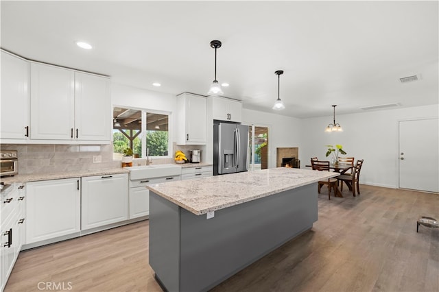 kitchen with white cabinets, a center island, light hardwood / wood-style flooring, sink, and stainless steel fridge with ice dispenser