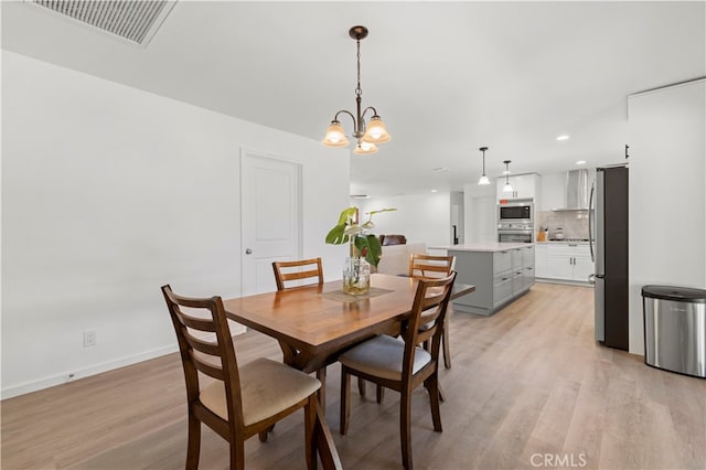 dining space with light hardwood / wood-style flooring and an inviting chandelier