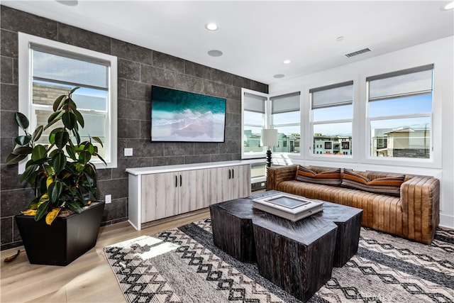 living room featuring a healthy amount of sunlight, tile walls, and light wood-type flooring