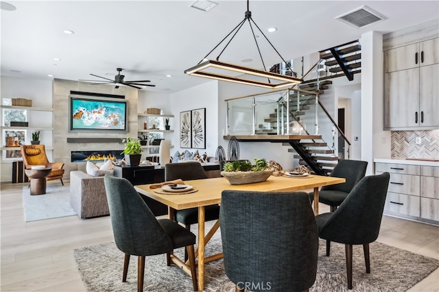 dining area with ceiling fan, light wood-type flooring, and a high end fireplace