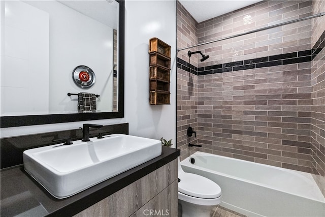 full bathroom featuring tiled shower / bath combo, vanity, and toilet