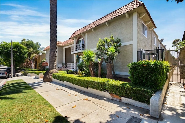 view of side of home featuring a tile roof, fence, and stucco siding