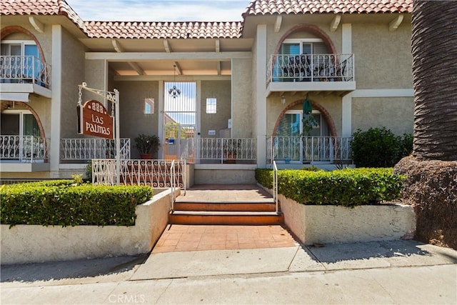 property entrance with a tile roof and stucco siding