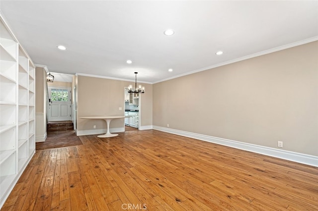 unfurnished living room with an inviting chandelier, light hardwood / wood-style flooring, and crown molding