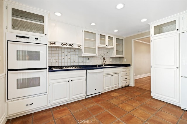 kitchen with backsplash, white appliances, and white cabinetry