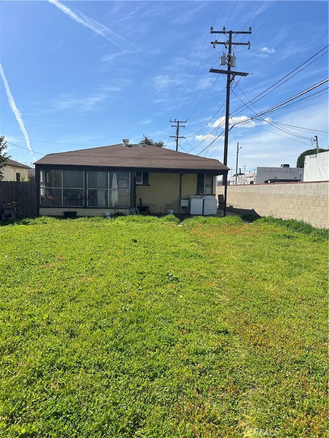 rear view of house with a sunroom and a lawn