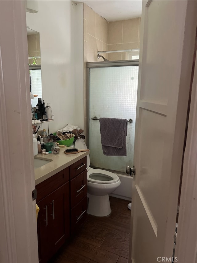 full bathroom featuring shower / bath combination with glass door, vanity, toilet, and hardwood / wood-style flooring