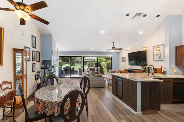 dining space with lofted ceiling, wine cooler, sink, and light hardwood / wood-style flooring