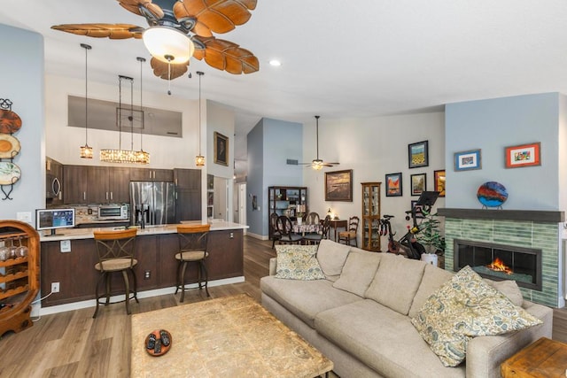 living room with vaulted ceiling, a tile fireplace, and light hardwood / wood-style flooring