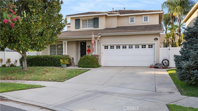 traditional-style home with driveway, an attached garage, fence, a front lawn, and stucco siding