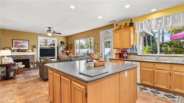 kitchen featuring a brick fireplace, open floor plan, a kitchen island, a sink, and dishwasher