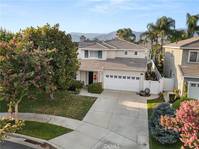 view of front of house featuring an attached garage, a mountain view, fence, concrete driveway, and a tiled roof