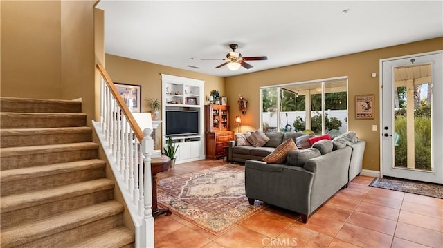 living room with ceiling fan, built in shelves, tile patterned flooring, baseboards, and stairway