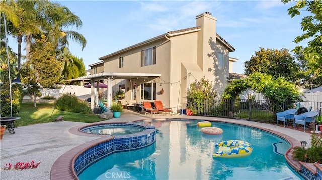 back of property featuring a patio area, fence, a pool with connected hot tub, and stucco siding