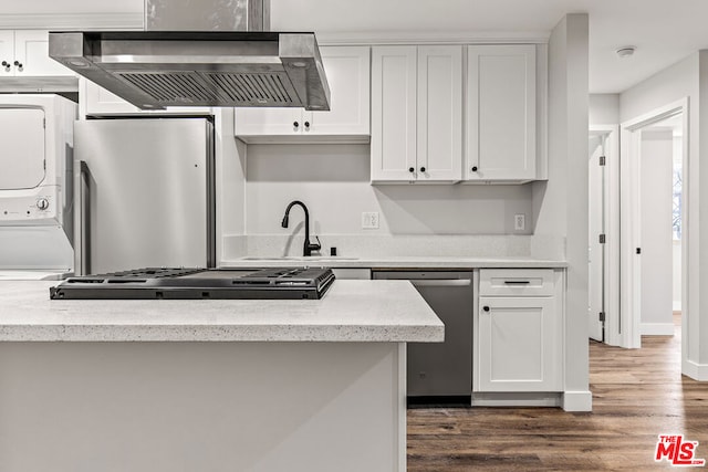 kitchen featuring appliances with stainless steel finishes, dark wood-type flooring, wall chimney range hood, and white cabinets