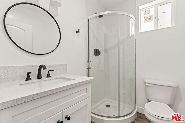 bathroom featuring wood-type flooring, vanity, toilet, and an enclosed shower