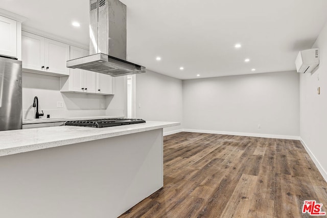 kitchen with island range hood, dark hardwood / wood-style floors, a wall mounted air conditioner, and white cabinetry