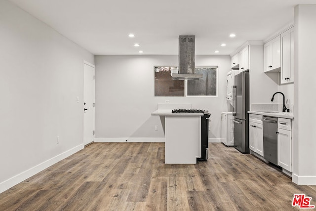 kitchen featuring wood-type flooring, sink, range hood, white cabinetry, and appliances with stainless steel finishes