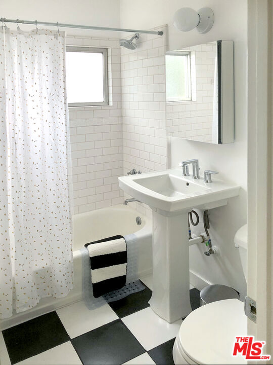 bathroom with toilet and shower / bathtub combination with curtain