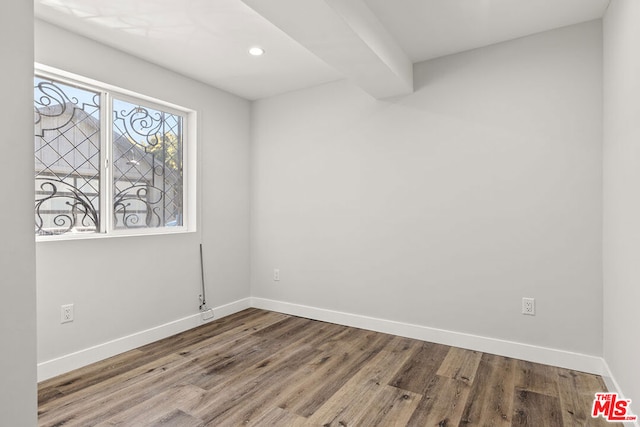 empty room featuring beam ceiling and hardwood / wood-style floors