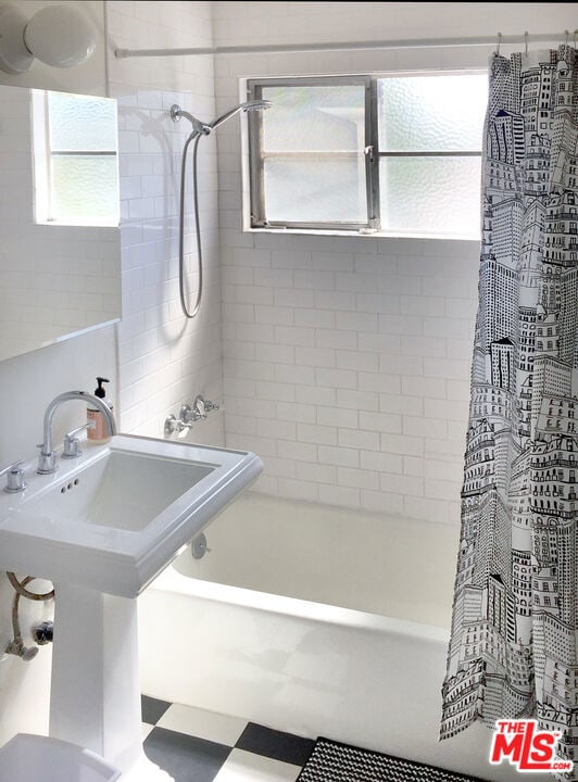 bathroom featuring shower / bath combo with shower curtain and sink