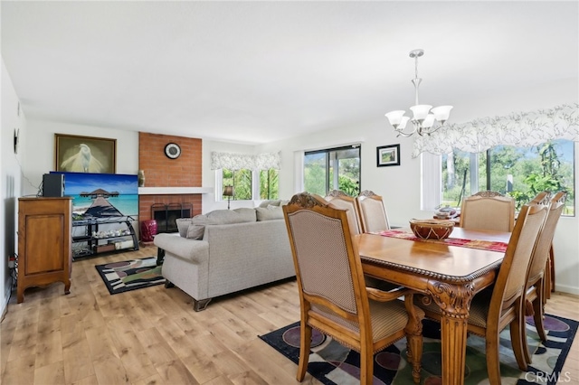 dining room with a brick fireplace, light hardwood / wood-style flooring, and a chandelier