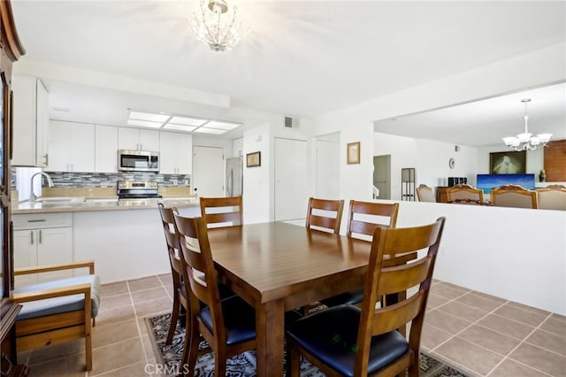 dining area featuring an inviting chandelier, light tile patterned floors, and sink