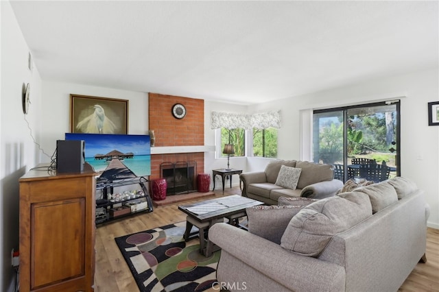 living room featuring a brick fireplace and light hardwood / wood-style floors