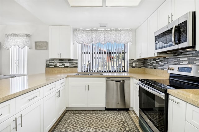 kitchen with sink, tasteful backsplash, white cabinetry, stainless steel appliances, and light stone countertops