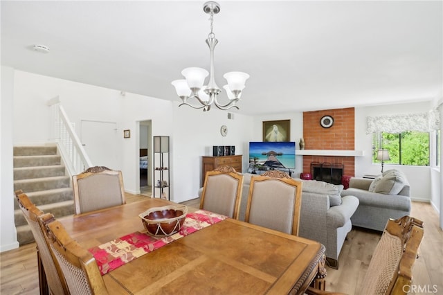 dining space with a notable chandelier, a fireplace, and light hardwood / wood-style floors