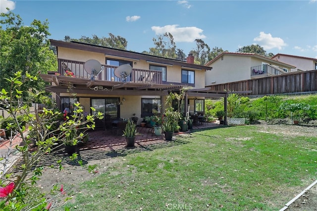 back of property featuring a pergola, a balcony, a yard, and a patio area