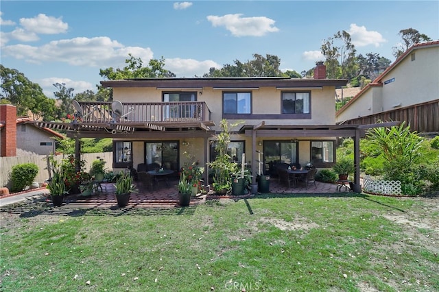 rear view of property featuring a yard, a balcony, and a patio area