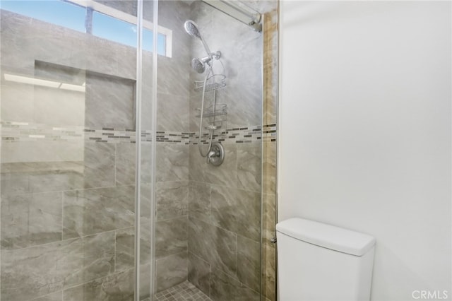 bathroom with a shower with door and toilet