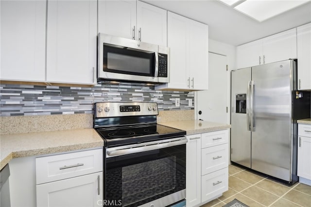 kitchen featuring appliances with stainless steel finishes, tasteful backsplash, light tile patterned floors, and white cabinets