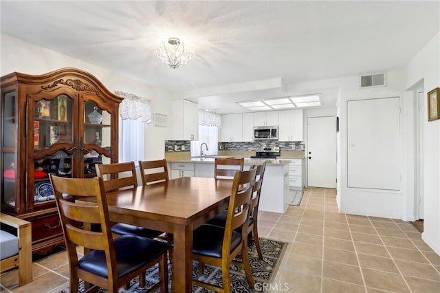 tiled dining room with an inviting chandelier and sink