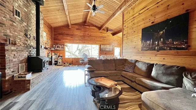 living room featuring hardwood / wood-style floors, wood walls, a wood stove, high vaulted ceiling, and beamed ceiling