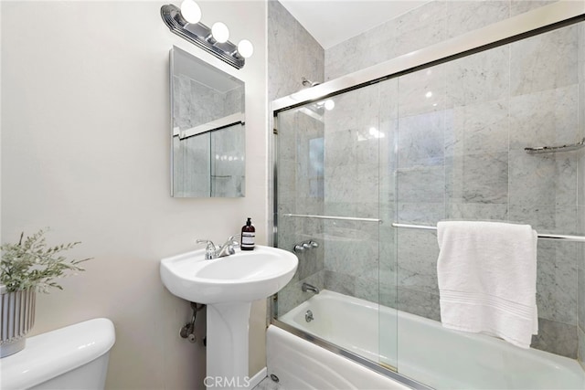 bathroom featuring toilet and combined bath / shower with glass door