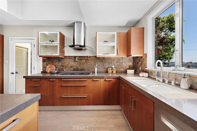 kitchen featuring sink, stainless steel gas cooktop, backsplash, wall chimney exhaust hood, and light hardwood / wood-style flooring