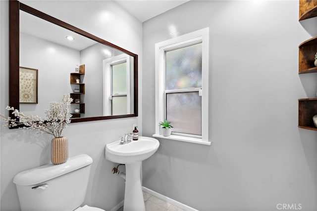 bathroom with toilet, sink, and tile patterned flooring