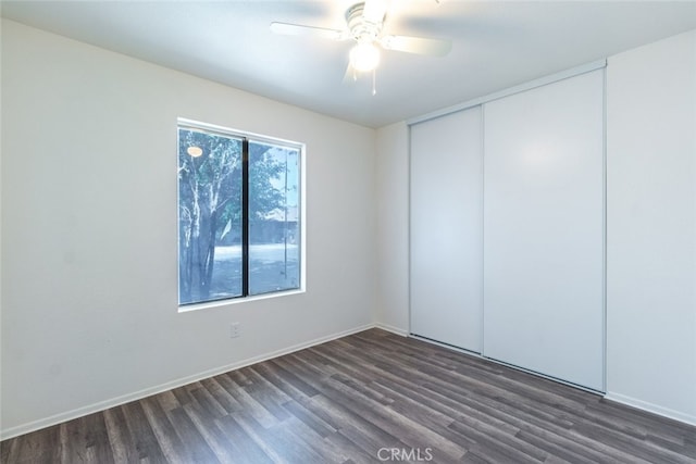 spare room featuring baseboards, ceiling fan, and dark wood finished floors