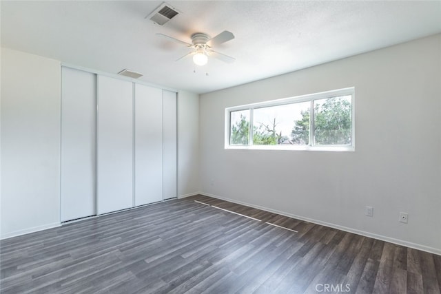 unfurnished bedroom featuring ceiling fan, a textured ceiling, a closet, and dark wood-type flooring