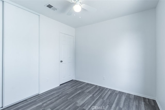 unfurnished bedroom with ceiling fan, dark wood-style flooring, visible vents, baseboards, and a closet