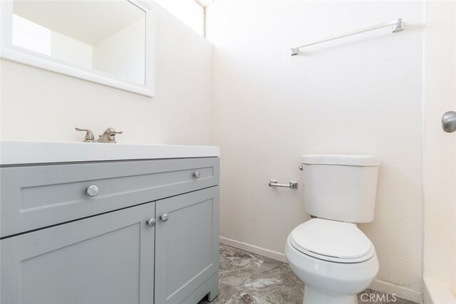 bathroom featuring baseboards, toilet, and vanity