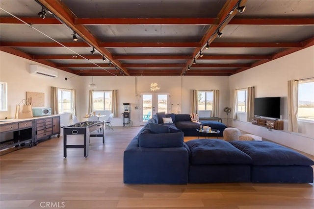 living room with french doors, an AC wall unit, wood-type flooring, and a wealth of natural light